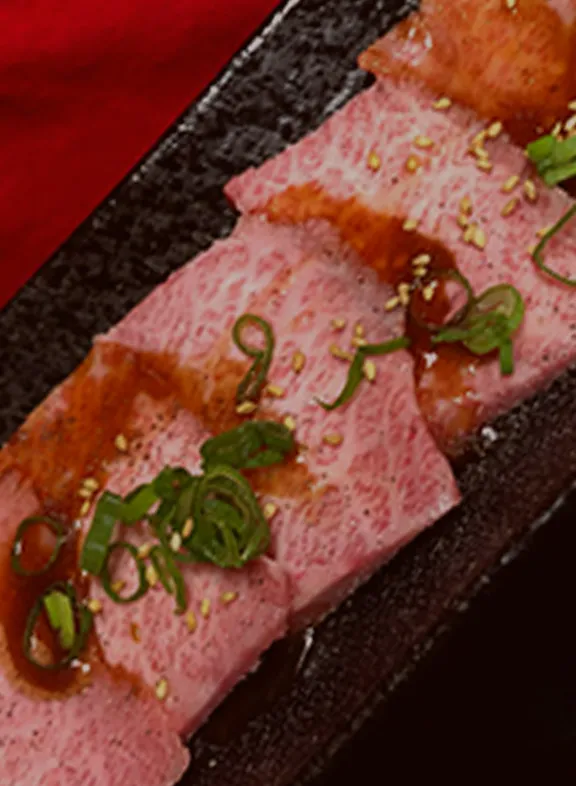 サシの入った和牛と焼肉が黒い皿に盛られている様子